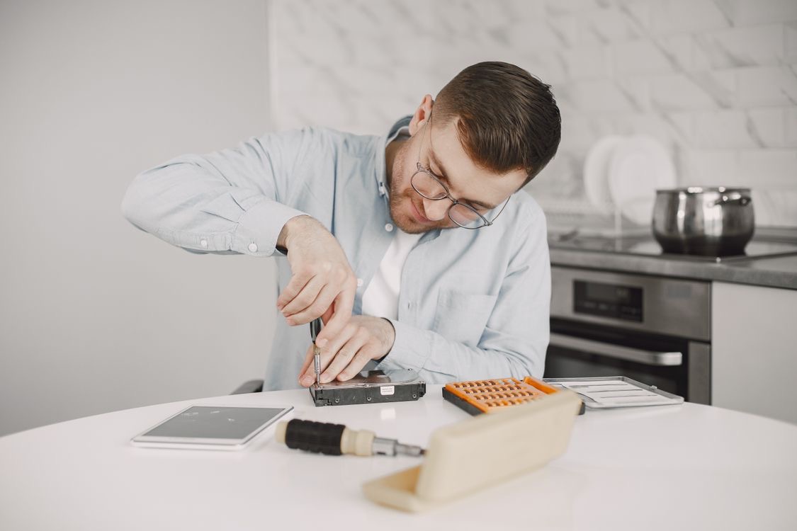 A person using a screwdriver on a small detached component at a table