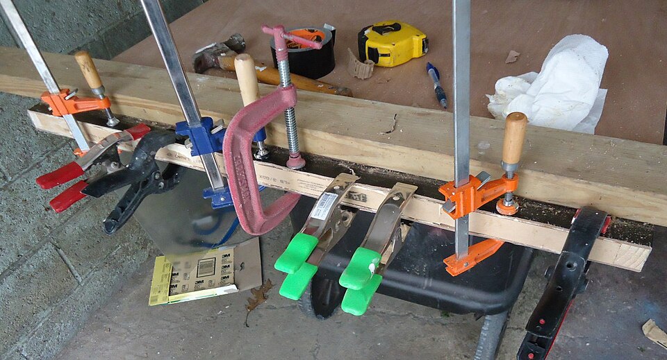 Several different clamps holding wood along the bottom edge of an interior door