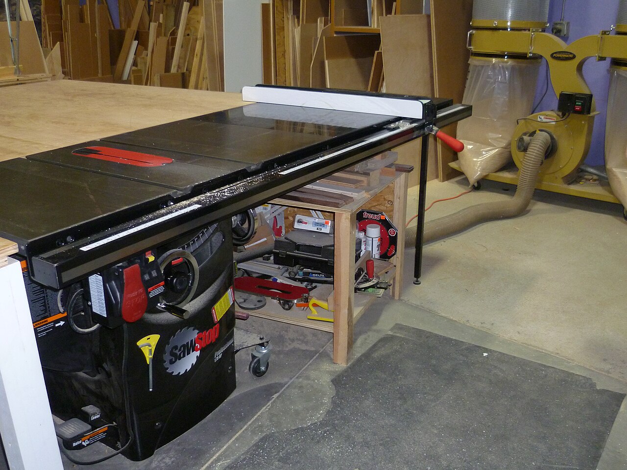 Parked woodshop table saw connected by a large flexible duct to a dust collector