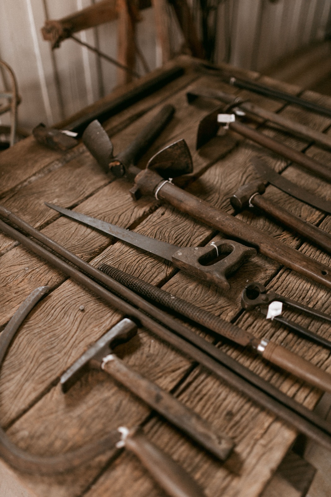 Older hand tools arranged across a rustic wooden workbench for inspection