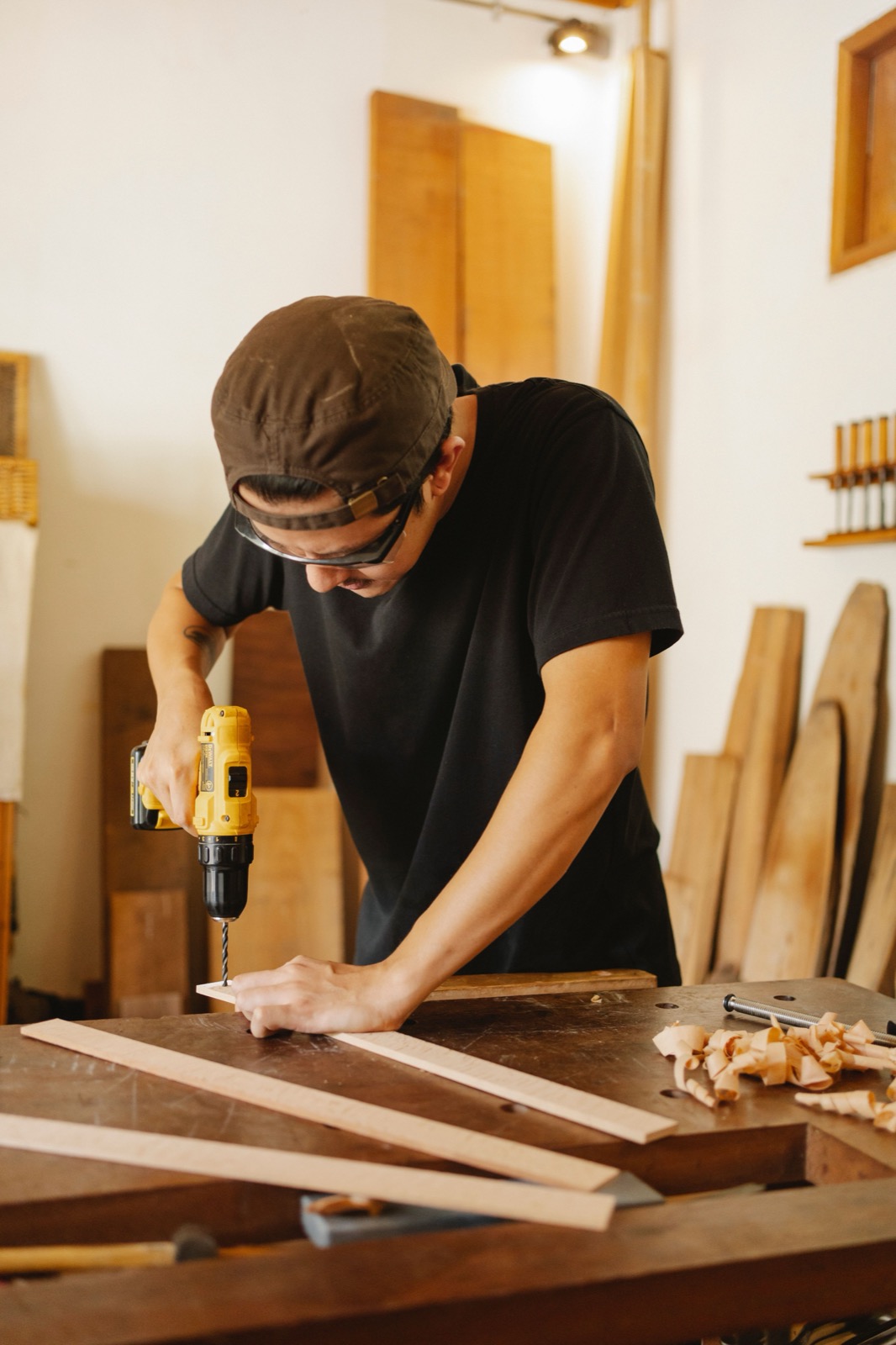 A person using a cordless drill at a woodworking bench