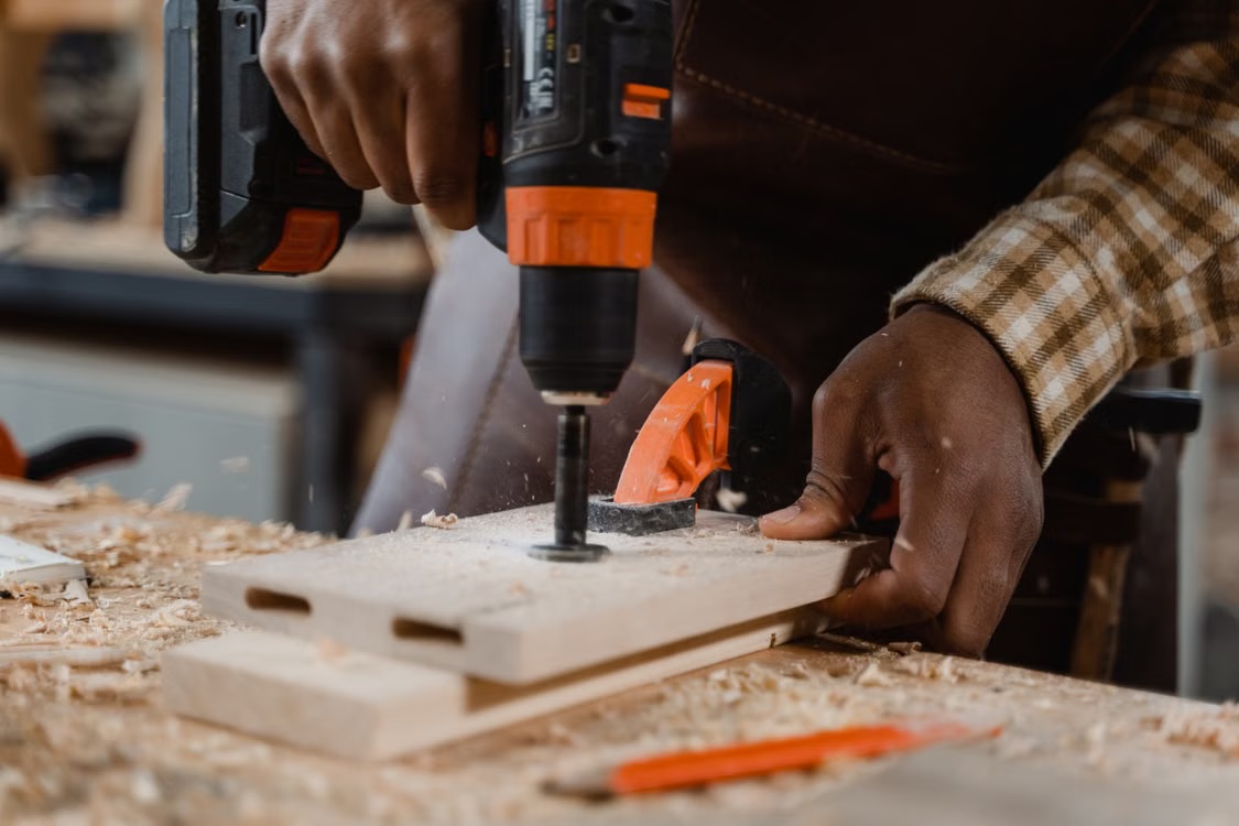 A woodworker drilling a clamped piece at a workbench